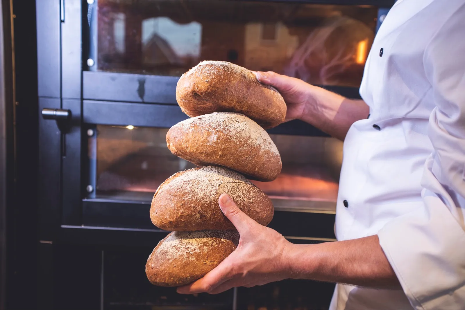 Bakker met versgebakken broden voor de oven